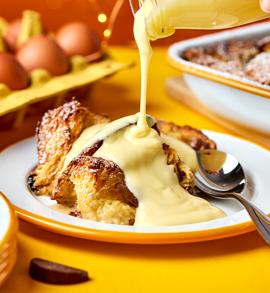 Terry's Chocolate Orange Panettone Bread & Butter Pudding with a glass jug of custard poured over the top
