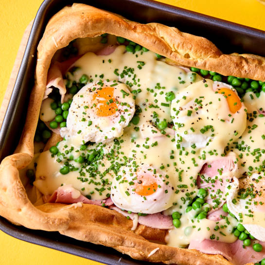 Giant Yorkshire pudding filled with ham and cheese sauce topped with chives